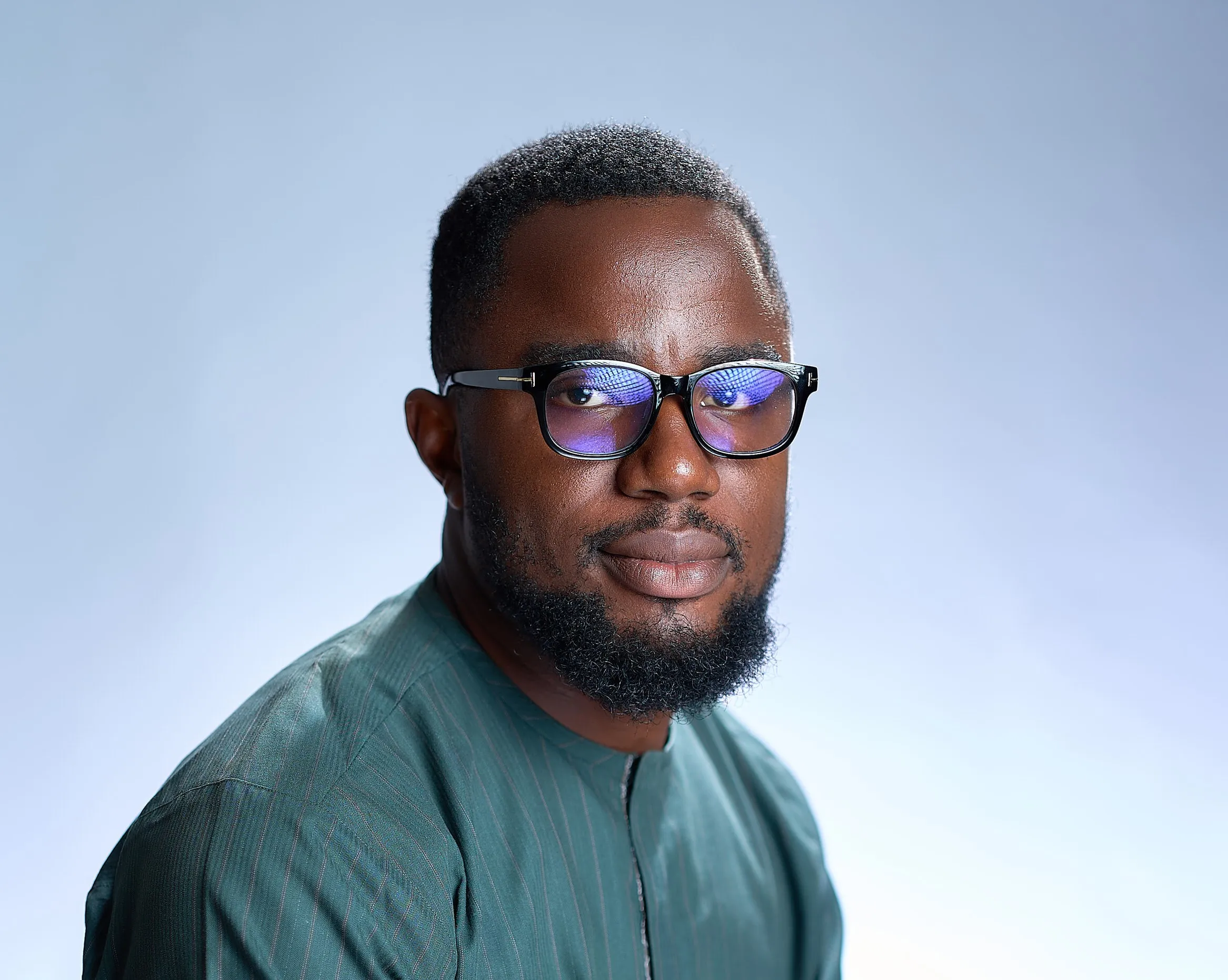 A picture of Oluwatosin Olowo with glasses and a beard wearing a green shirt.