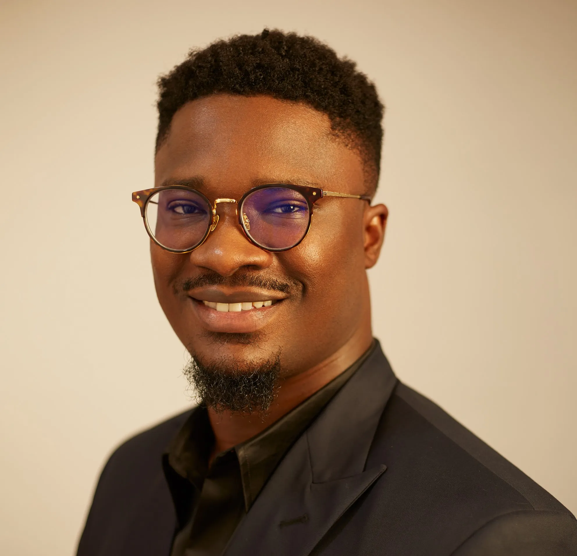A photo of the CEO, Seye Bandele wearing glasses and a suit.